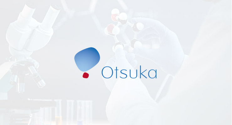 A person wearing gloves holds a molecular model beside a microscope, with the Otsuka logo and name displayed prominently in the foreground, highlighting insights from a pharma Storage and Virtualisation Case Study.
