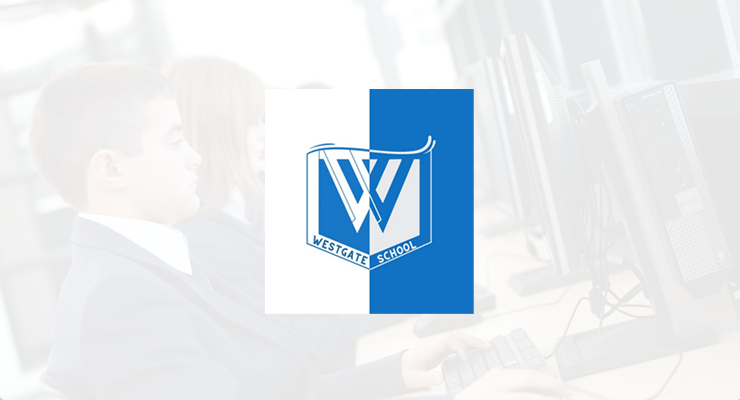Westgate School logo centred over a blurred background of students using desktop computers in a classroom, illustrating a scene from the IT Infrastructure Case Study or PRTG Case Study.
