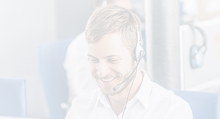 A man wearing a headset and white shirt is sitting at a desk, smiling while working in an office environment with Call Recording Archival systems.