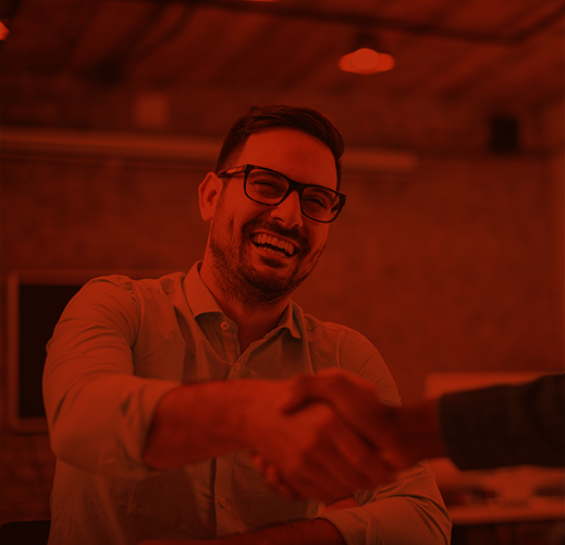 A smiling man with glasses, a Dell partner, shaking hands in an office setting, with a warm red filter overlay.