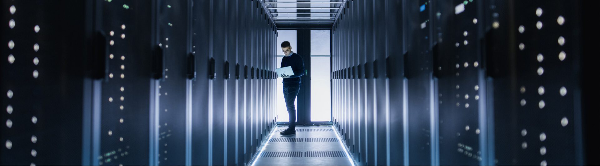 A person in a dark suit, a Dell partner, stands in a brightly lit data center, looking at servers.