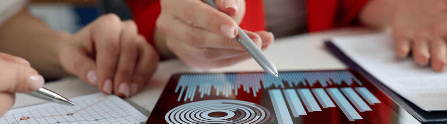 Two professionals analysing financial data on a digital tablet with graphs and charts displayed on the screen.